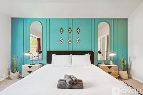 A bedroom with a large bed and a mirror on the wall.