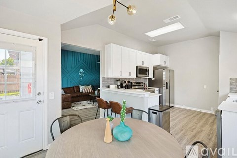 A modern kitchen with white cabinets and a dining table set with a vase and two chairs.