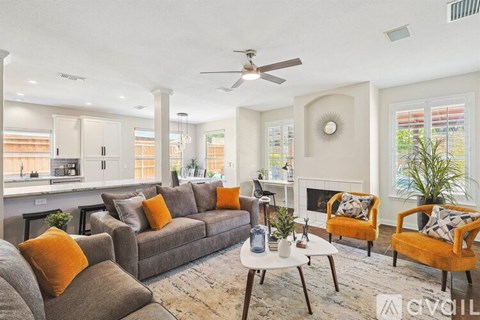 A living room with a grey couch and orange pillows.