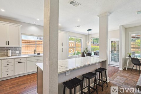 A kitchen with white cabinets and a marble countertop.