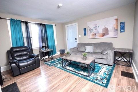 A living room with a black leather chair and a grey couch.