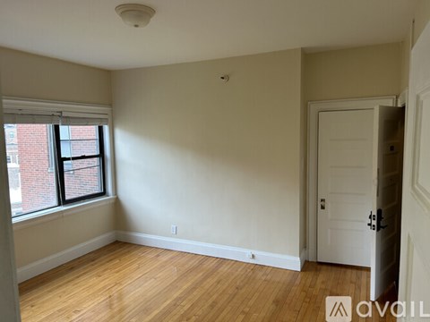 A room with a white door and a window with a view of a brick building outside.