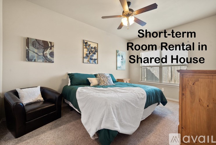 A bedroom with a bed, chair, and ceiling fan is available for short-term room rental in a shared house.