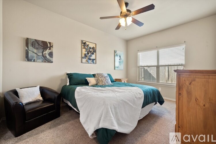A bedroom with a bed, a chair, and two pictures on the wall.