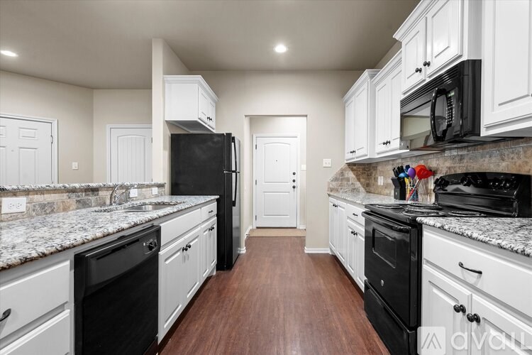 A kitchen with black appliances and white cabinets.
