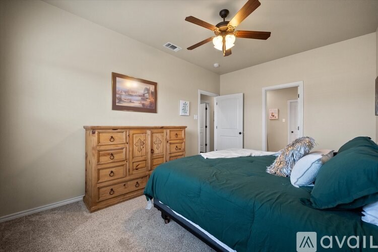 A bedroom with a bed, dresser, and ceiling fan.