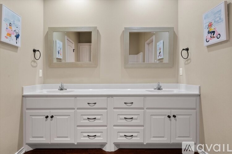 A white bathroom vanity with two sinks and two mirrors above it.