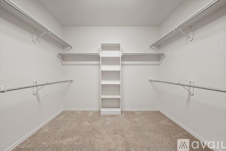 A room with a carpeted floor and a white wall with a shelf and a ladder.