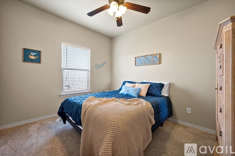 A bedroom with a bed, a ceiling fan, and two pictures on the wall.