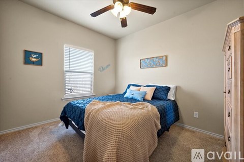 A bedroom with a bed, a ceiling fan, and two pictures on the wall.