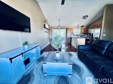 A living room with a black couch and a television on the wall.