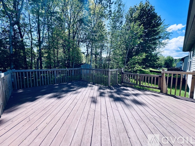 A wooden deck with a railing and trees in the background.