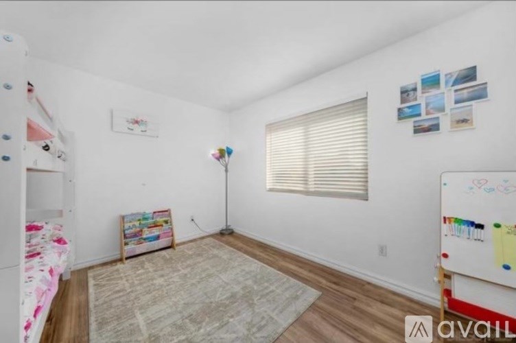 A room with a white wall and a window with blinds.