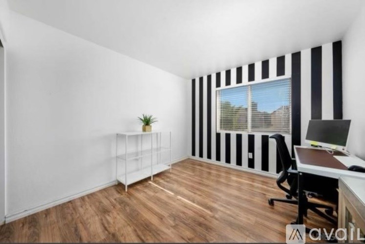 A room with a desk, chair, and a plant.