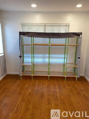 A room with a wooden floor and a shelving unit with green and white stripes.