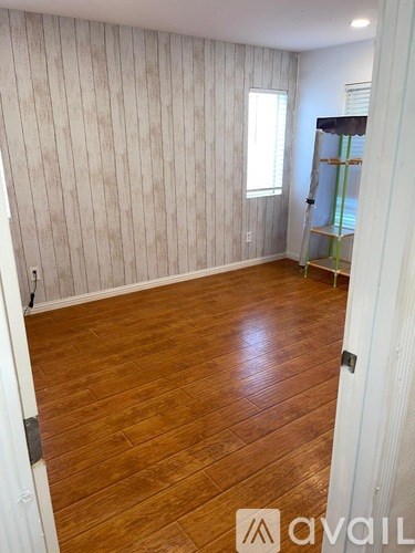 A room with wooden flooring and a white wallpapered wall.