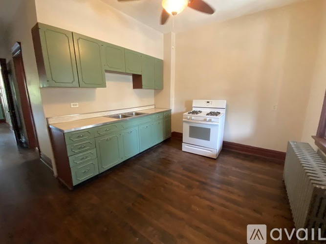 A kitchen with green cabinets and a white stove top oven.