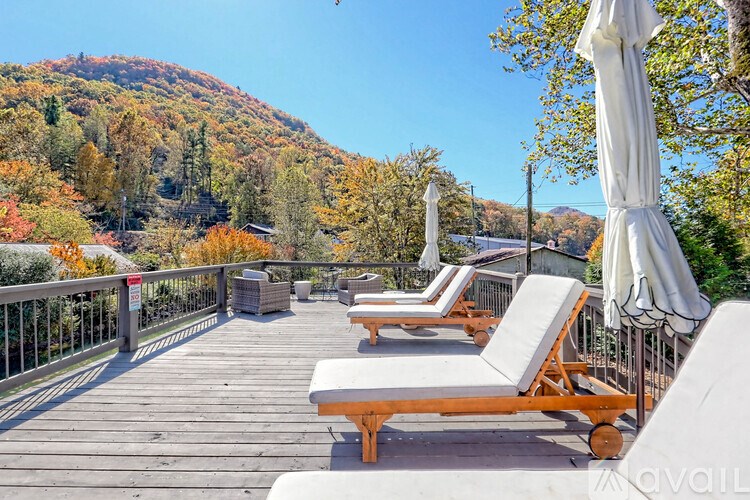 A deck with sun loungers and umbrellas overlooking a mountain.
