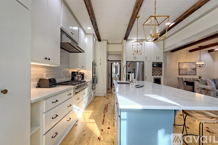 A modern kitchen with white cabinets and a wooden floor.
