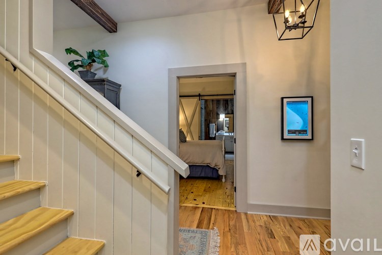 A staircase with wooden steps and white railings leads to a room with a bed and a window.