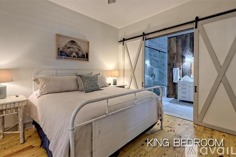 A bedroom with a bed, nightstand, and a window with a view of a city street.