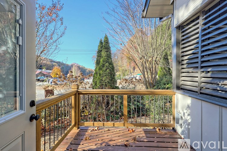 A wooden deck with a metal railing and a view of trees and houses in the distance.