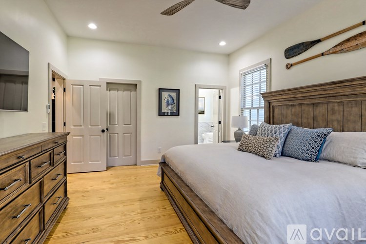 A bedroom with a large bed, wooden dresser, and a ceiling fan.