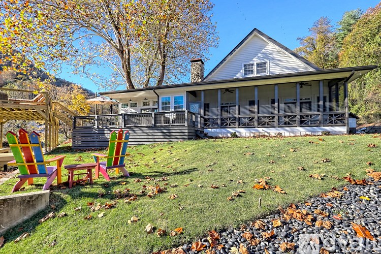 A house with a porch and two chairs in front of it.