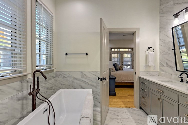 A bathroom with a marble tub and a window with blinds.