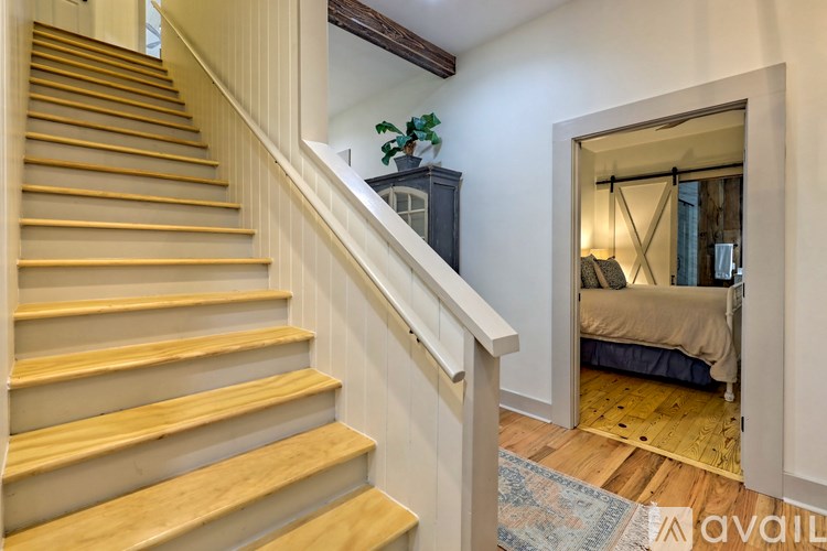 A wooden staircase leads to a bedroom with a bed and a mirror.