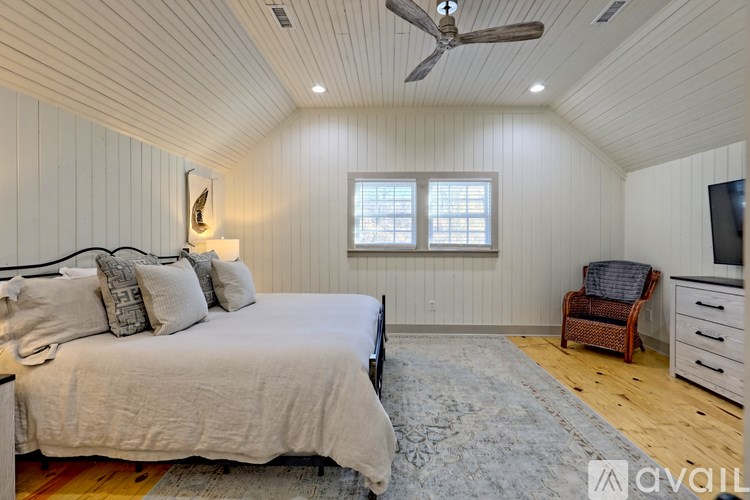 A bedroom with a bed, chair, and ceiling fan.