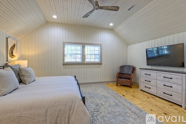 A bedroom with a bed, chair, and a television.