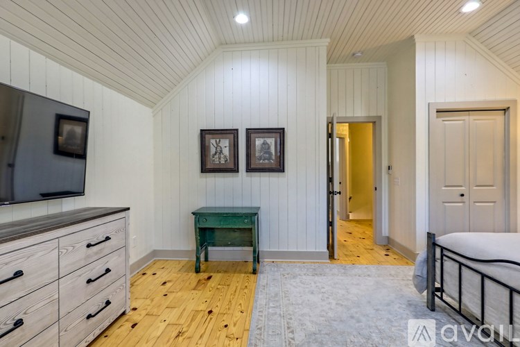 A bedroom with a bed, dresser, and a green table.