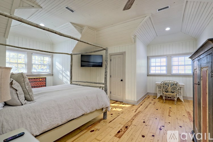 A bedroom with a bed, a chair, and a television.