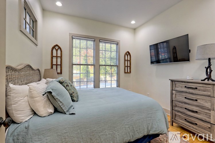 A bedroom with a bed, a dresser, and a television.