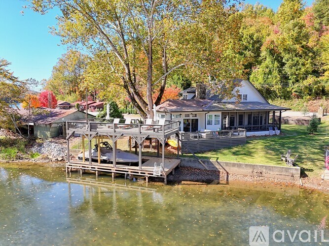 A house with a deck overlooking a body of water surrounded by trees.