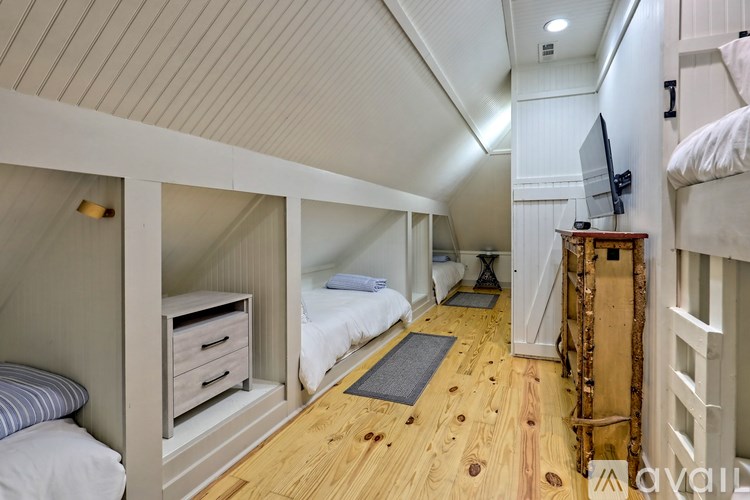 A bedroom with a bed, a dresser, and a TV mounted on the wall.