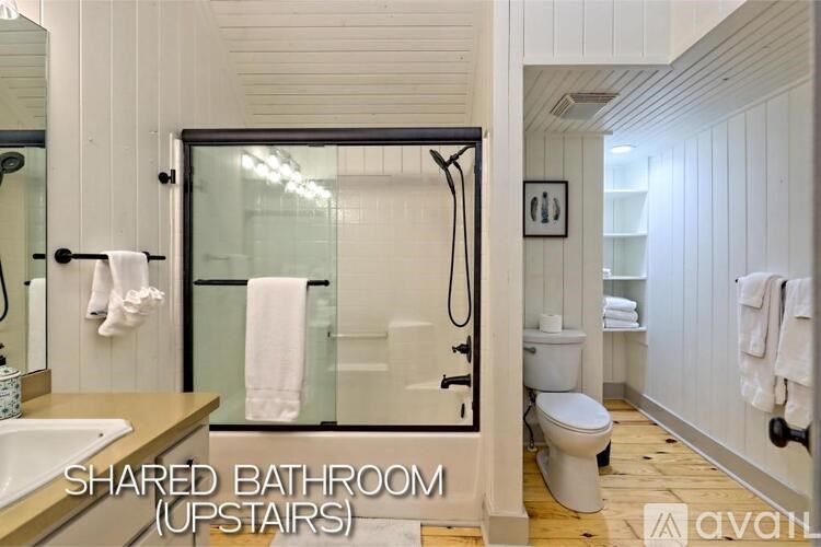 A shared bathroom with a toilet, sink, and shower.