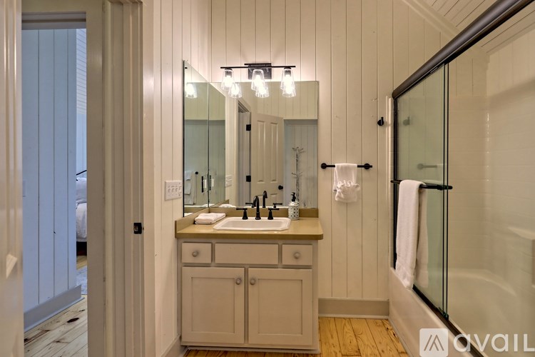 A bathroom with a sink, mirror, and shower.