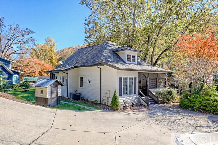 A house with a grey roof and a small shed in front of it.
