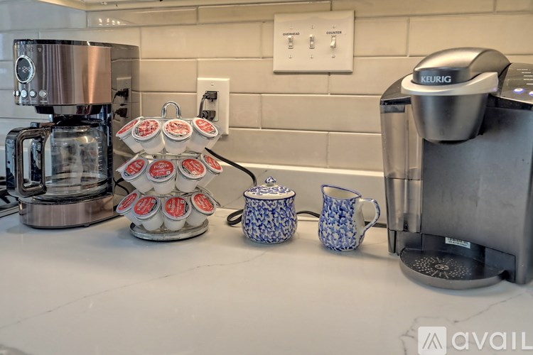 A Keurig coffee maker is on a counter next to a stack of cups.
