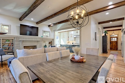 A modern living room with a wooden floor and a large wooden table in the center.