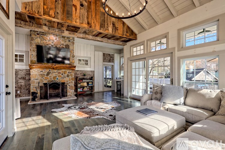A living room with a stone fireplace and a chandelier.