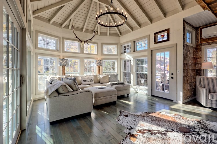 A large, well-lit living room with a high ceiling and a chandelier.