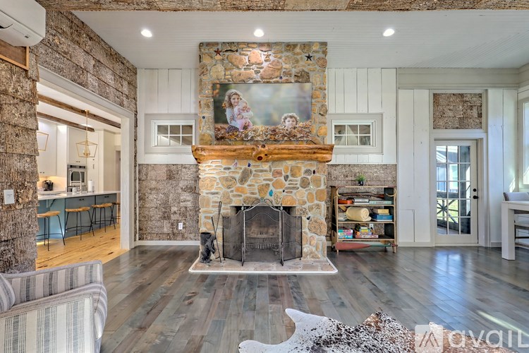 A living room with a stone fireplace and a painting above it.