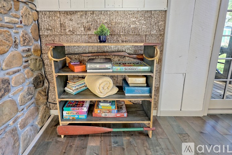 A wooden bookshelf with various books and a plant on top.