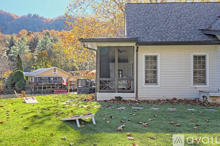 A house with a white exterior and a grey roof with a small porch and a bench.