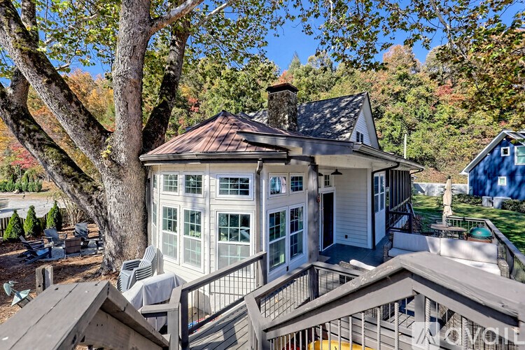 A house with a white exterior and a brown roof is surrounded by trees.