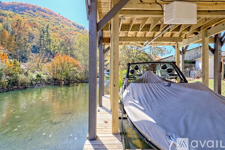 A boat is covered with a grey tarp and is docked at a wooden pier.