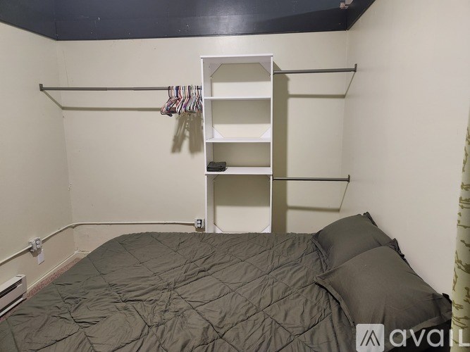A bedroom with a bed, pillow, and a shelf.